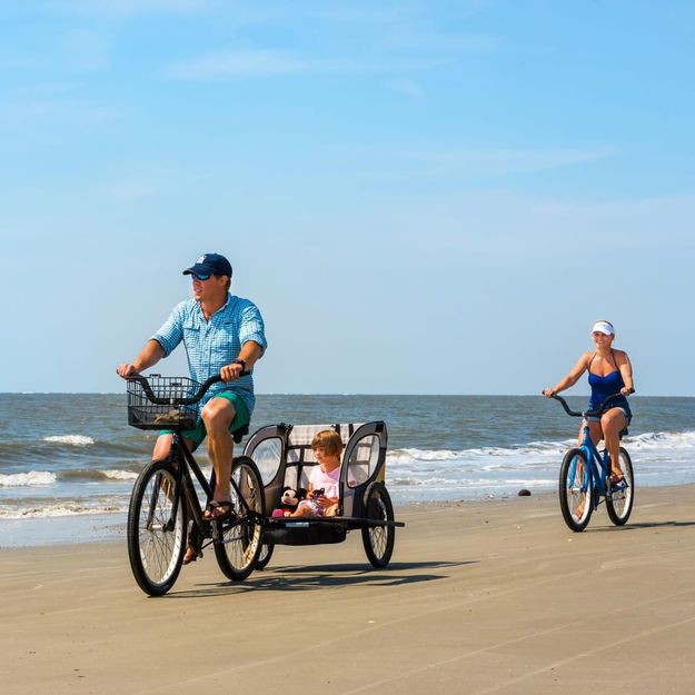 A family of three riding bicycles on the beach