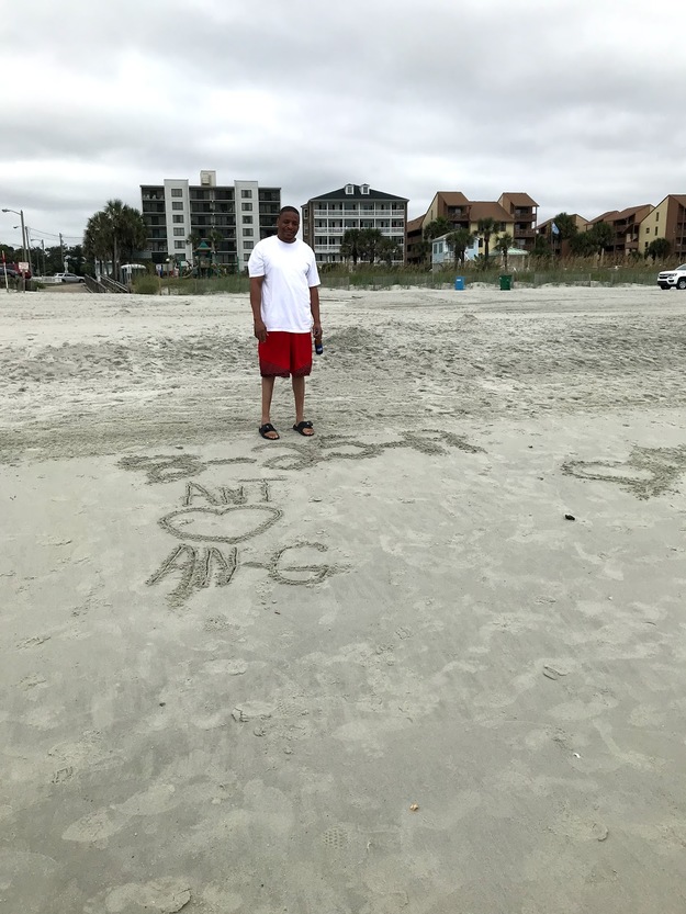 Man on the beach looking at the words written on the sand