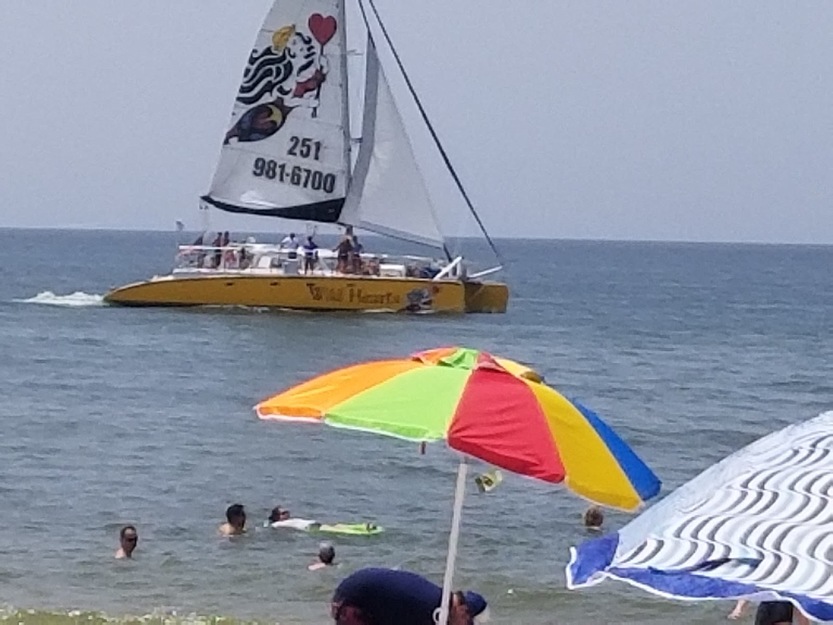 Boat sailing in the sea and umbrellas on the beach