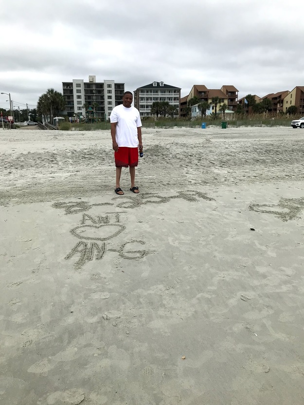 Man on the beach looking at the words written on the sand